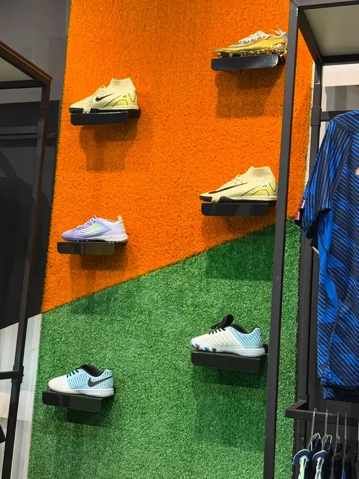 Parede laranja e verde com chuteiras expostas