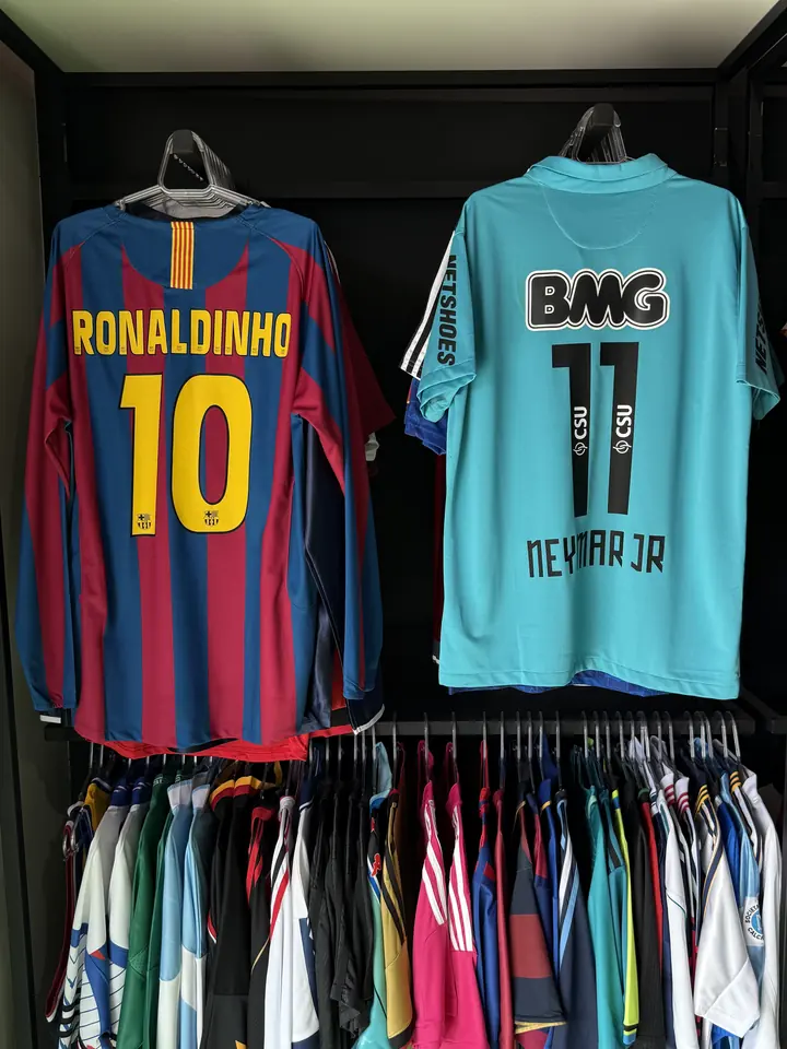 Camisas retrô do Barcelona com o 10 do Ronaldinho e do Santos com o 11 do Neymar penduradas na arara